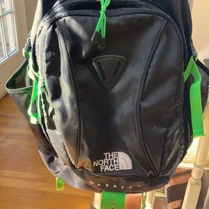 The North Face Wasatch black backpack with green trim.